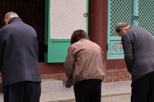 Three individuals wearing jackets bowing with their backs to the camera