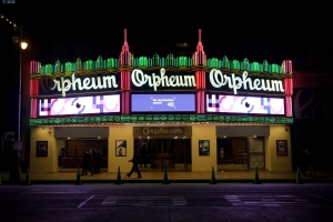 Photo of the outside of a theater, with a lit up marquee of the 40th IDA Documentary Awards' pink and purple graphics.