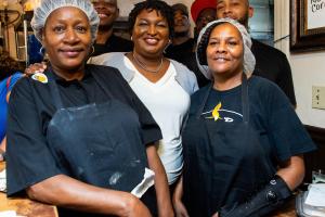 Group of African-American is smiling at the camera in a kitchen.