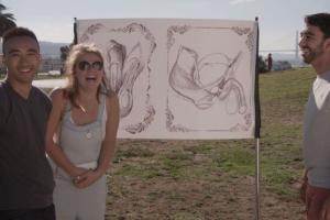 Three people standing in front of a drawing of human genetalia.