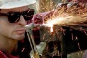 man in white hard hat soldering. 