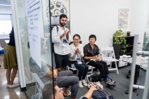 In a small office, a group of young filmmakers sit in chairs.