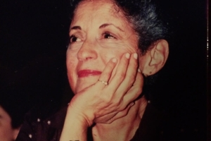 Image of Arlene Carmen, a white woman in her 40's with curly dark hair.  She is smiling and resting her face in hand; she is wearing a gold ring and a wristwatch.