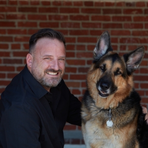 Headshot of Brian Davis accompanied by his German shepherd dog Deuce