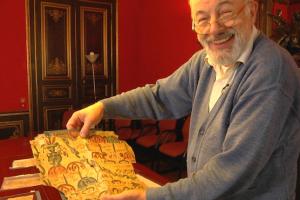 A Caucasian man is holding up an ancient scroll while smiling.
