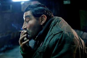 A man smokes in a darkened screening room