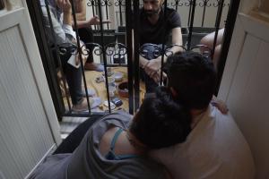 Two individuals talking to three people across a black fence.