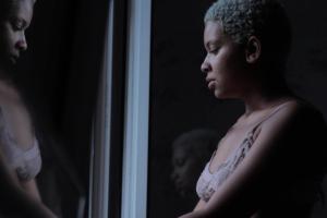 An African-American female looking at herself through the mirror.