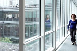 A woman is walking through a glass hallway in an art museum.
