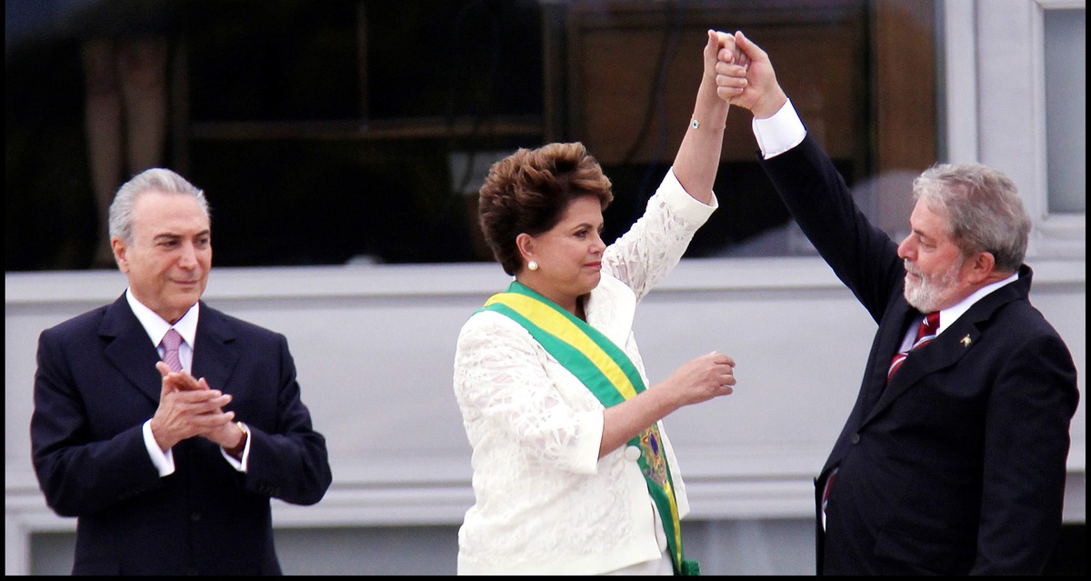 Dilma Rousseff, the former president of Brazil, is applauded while Luiz Inácio Lula da Silva, her predecessor, who was just elected president for the second time, on October 30, 2022, raises her hand in the air. From Petra Costa’s ‘The Edge of Democracy.’ Photo courtesy of Netflix.