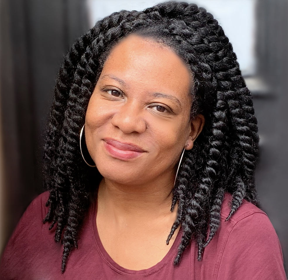 Photograph of Erika Dilday, a young Black woman smiling wearing hoop earrings.