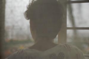 a face stares out the window on a cloudy day
