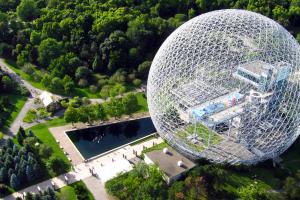 A geometric steel dome sits on a green landscape. 