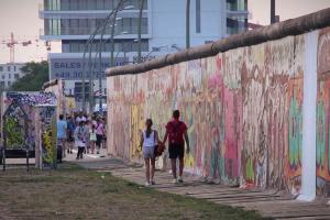 A young couple walks along a preserved segment of the Berlin Wall in 2014