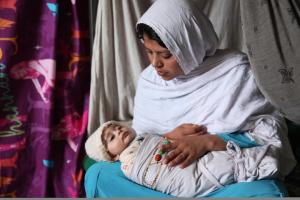 A woman in Hijab is holding her child.