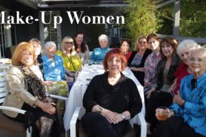 Thirteen elderly White  women sit around a white patio table facing the camera. 
