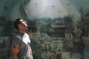 A man is looking up in front of a wall painting.