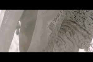 A person looks through a white veil.