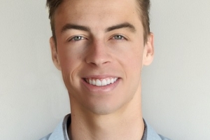Reed Martin. A man with white skin smiles at the camera. He has short, brown hair, blue eyes and is wearing a blue collared shirt.