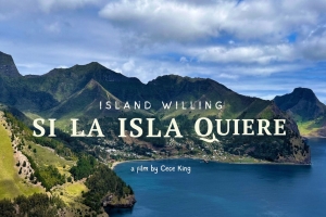 A volcanic archipelago is vividly green and surrounded by blue ocean. Nestled in the middle is a small town. Text overlays the image. The biggest in the middle says "SI LA ISLA QUIERE" with the English translation "Island Willing" above and "Film by Cece King" below.