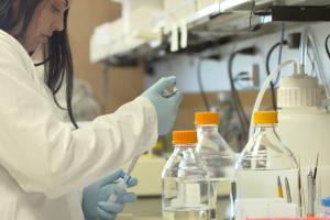 a female scientist loads a vial in a scientific lab.