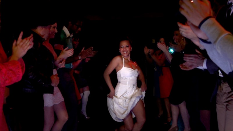 A woman in a white dress dances while people clap around her. From Mathew Ramirez Warren’s 'We Like It Like That.' Courtesy of 'We Like It Like That' and 'America ReFramed.'
