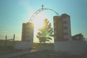 Wounded Knee Memorial arch framing a tree with a ray of sunlight