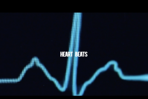 Heart Beats in white lettering over a background of a heart monitoring machine.