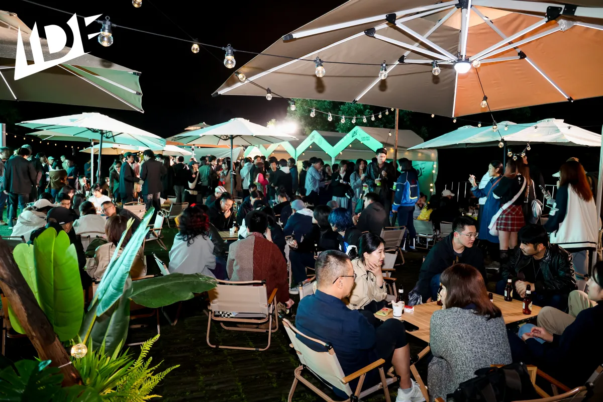 Under rain umbrellas, hundreds of festivalgoers chat and drink during a party.