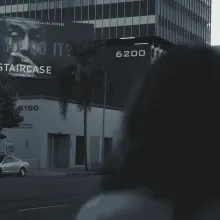 Margaret Ratliff is a white woman. Her back faces the camera as she looks at a billboard advertising the TV series ‘The Staircase.’ From Jennifer Tiexiera and Camilla Hall’s ‘Subject.’ Photo courtesy of Susan Norget Film Promotion.  