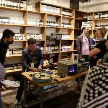 In a room with shelves lined with tapes, a group of people gather around a table with film materials.