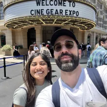 Selfie of a man and woman standing in front of a sign reading “Welcome to Cine Gear Expo.”