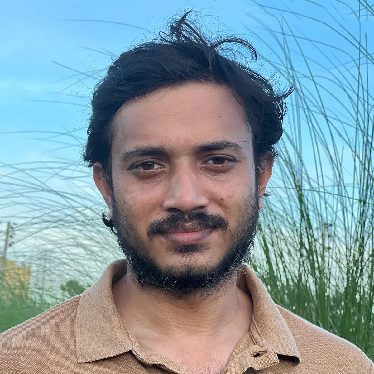 Headshot of a middle-aged male of South Asian descent in a brown polo shirt.