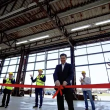 An AI-generated video of a factory floor with glass walls and a man in a black suit holding a floating red ribbon.