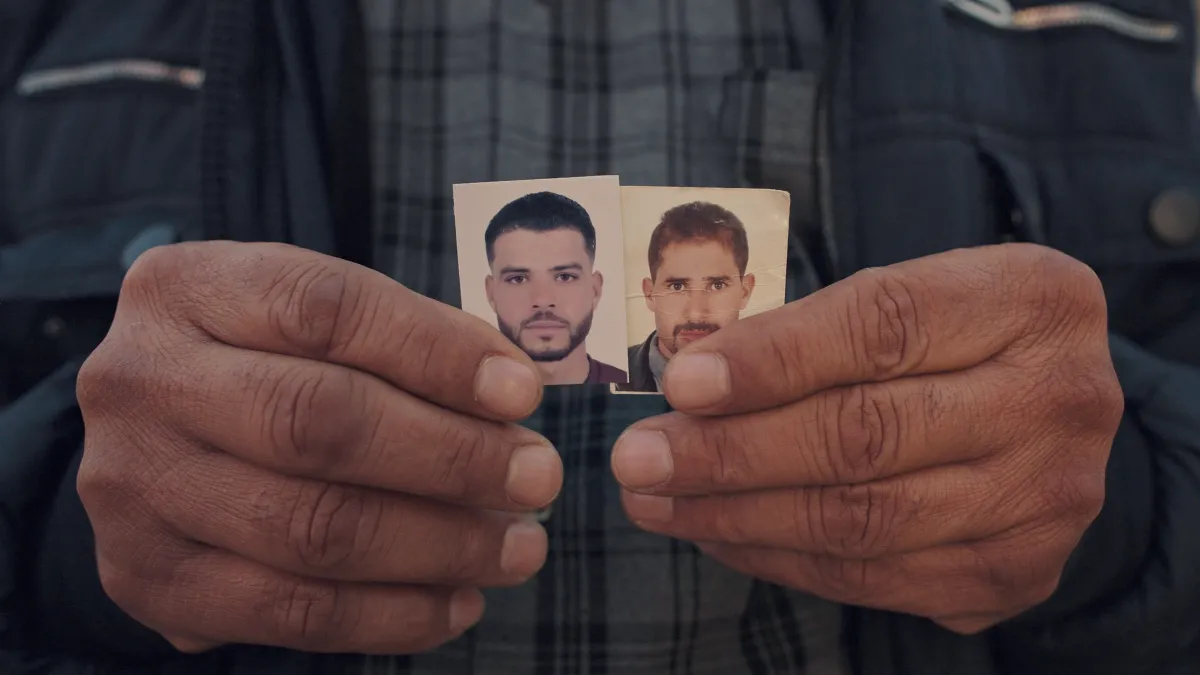 hands hold two small pictures of young men side by side