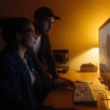 Two filmmakers work at a computer desk.