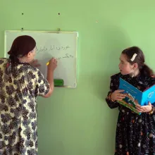 Film still from 'Writing Hawa' featuring two women - one with a book in hand, the other writing on a whiteboard.